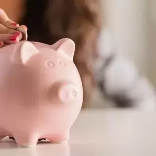 Woman putting money in a pig-shaped bank