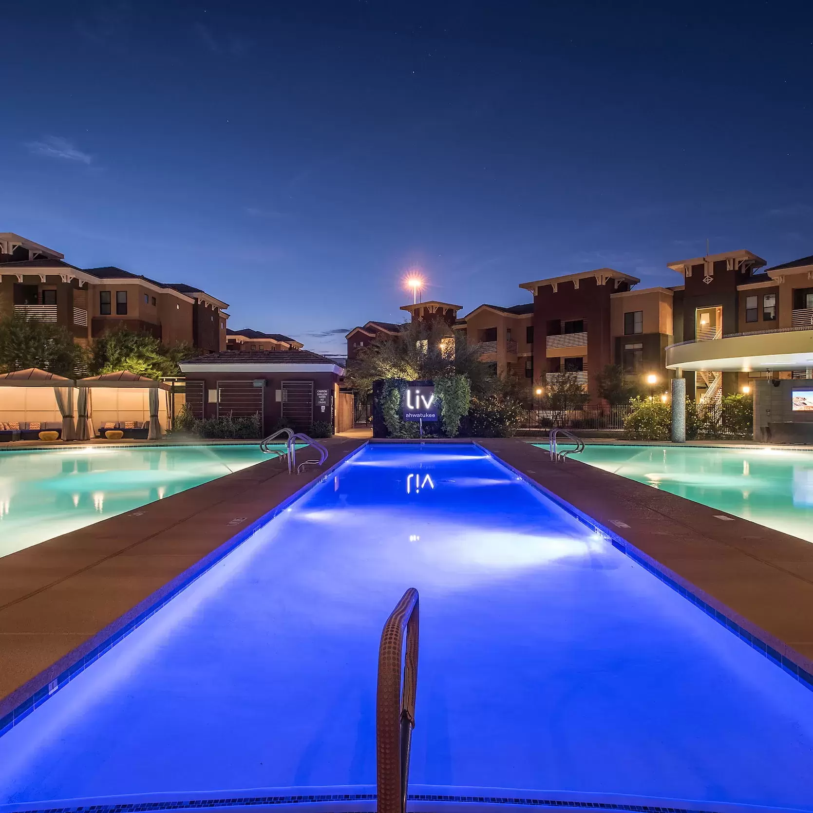 The pools lit up at night under a clear sky at Liv Ahwatukee.