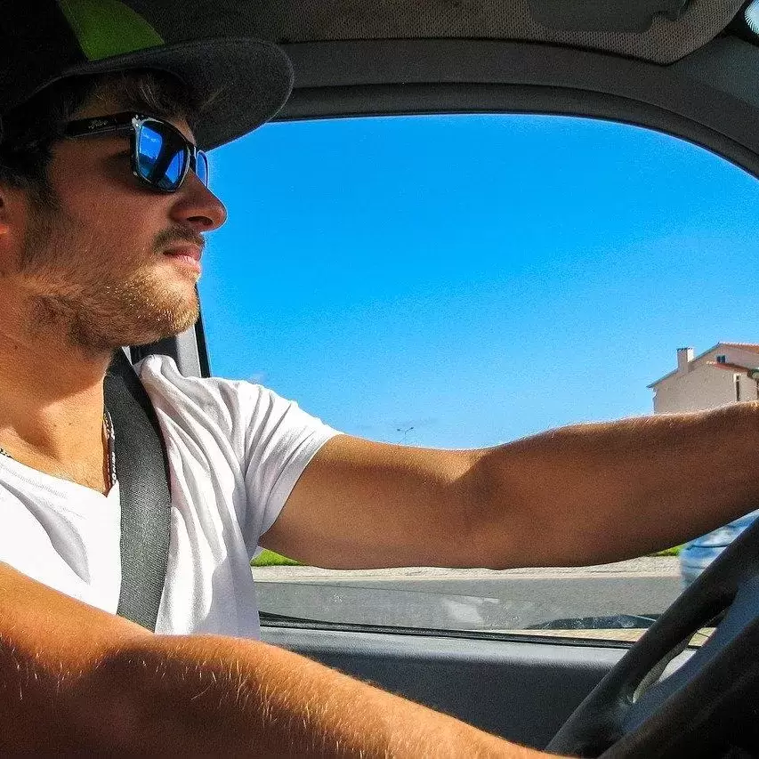 A man wearing sunglasses driving a car.